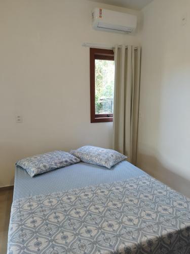 a bed in a bedroom with a window at Recanto das Amendoeiras in Guarda do Embaú