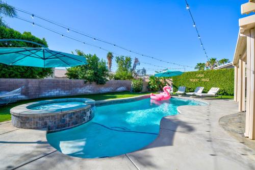 a swimming pool with a pink flamingo and an umbrella at Casa Desert Muse with Heated Pool Spa Firepit Mini Golf and Games in Indio
