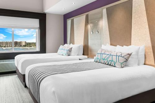 two beds in a hotel room with a window at Best Western Premier Winnipeg East in Winnipeg