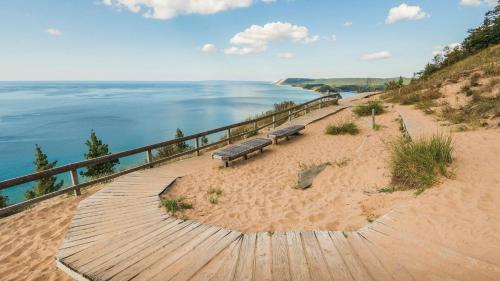 two benches sitting on a boardwalk next to the beach at Driftwood Dreams 1B in Traverse City