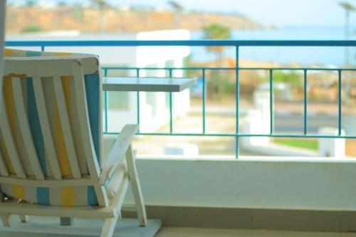 Ein Schaukelstuhl steht neben einem Tisch auf einem Balkon. in der Unterkunft El Kheima Beach Resort in Sharm El Sheikh