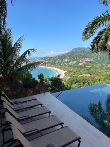 a group of chairs sitting on a balcony overlooking a beach at Luxury Residence at Vista Bay 103 in Zihuatanejo
