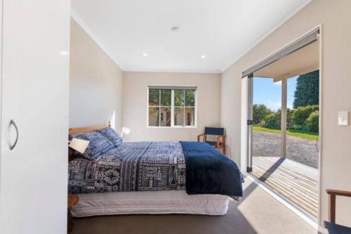 a bedroom with a bed and a balcony at Grace Cottage in Turangi