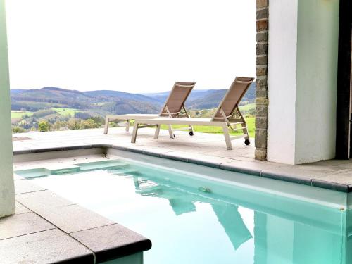 a pair of chairs sitting next to a swimming pool at Les Charmes in Chevron
