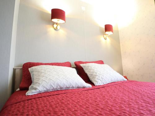 a bed with two red and white pillows and two lights at Les Charmes in Chevron