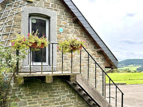a stone building with two windows with flowers on it at Les Charmes in Chevron