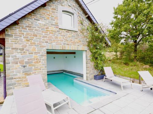 a backyard pool with white chairs and a brick building at Les Charmes in Chevron