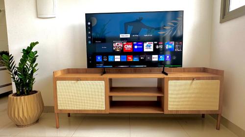 a tv on a wooden tv stand in a room at Apt Araras - Próximo ao Shopping in Palmas