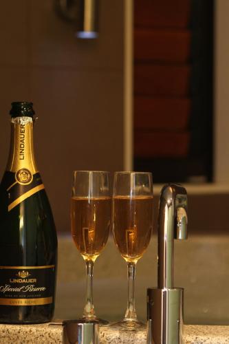 two glasses of wine next to a bottle of champagne at Bentleys Motor Inn in Palmerston North