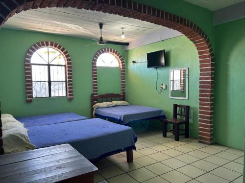 a bedroom with two beds in a room with green walls at Hotel Libramiento Puerto Vallarta in Puerto Vallarta
