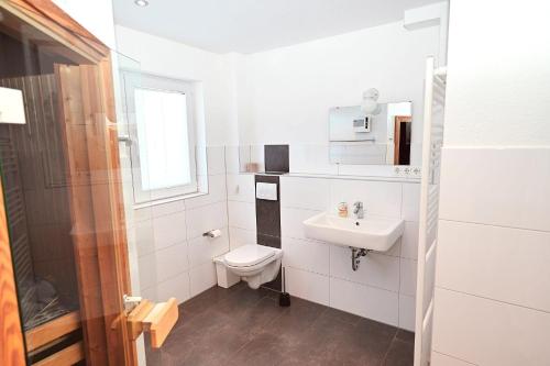a white bathroom with a toilet and a sink at Sechendorf-Ferienhaus-Solhem-Sechendorf in Blekendorf