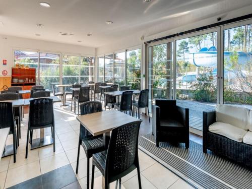 un restaurant avec des tables, des chaises et des fenêtres dans l'établissement House near Lake Biscarrosse, à Parentis-en-Born