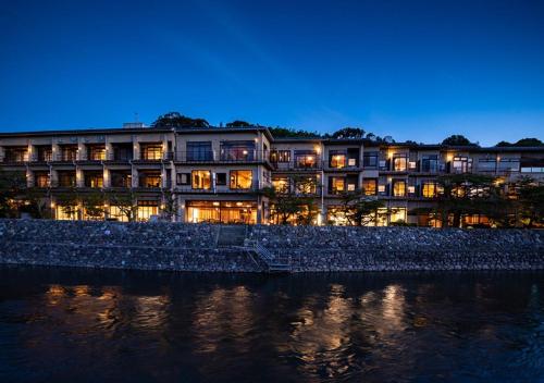 a hotel is lit up at night next to the water at Hanayashiki Ukifune-en in Uji