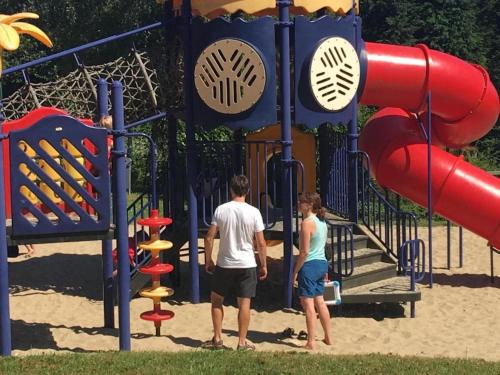 two people standing in front of a playground at Glamping Lodge in the Ardennes in Olloy-sur-Viroin