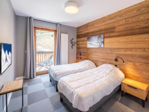 - 2 lits dans une chambre avec un mur en bois dans l'établissement Chalet in Auris-en-Oisans with Balcony, à L'Alpe-d'Huez