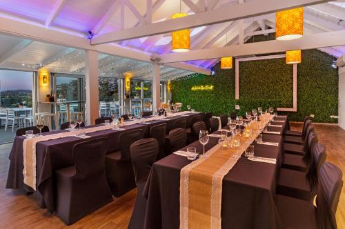 a dining room with long tables and black chairs at Waiheke Island Resort Conference & Accomodation Centre in Ostend