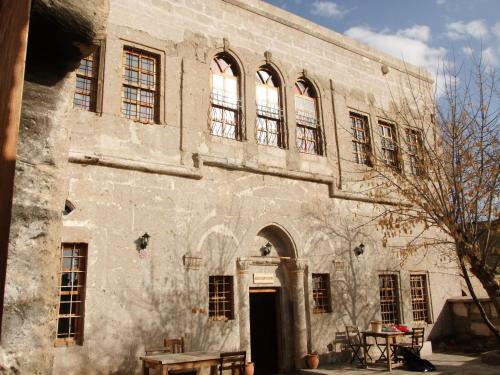 an old stone building with a table in front of it at Kapadokya Ihlara Konakları Otel Konak Odaları in Guzelyurt