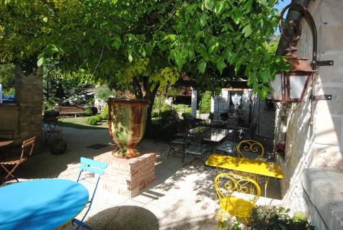 Le Grand Logis - Guest house - Bed and Breakfast في Marchais: فناء مع مزهرية كبيرة وكراسي تحت شجرة