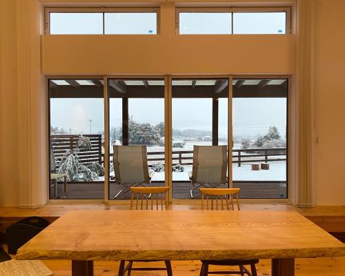 a large room with a table and chairs and windows at 一棟貸切Azumino36Stay 安曇野の静かな隠れ家 貸切サウナ BBQ 絶景テラス in Azumino