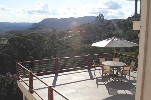 a balcony with a table and chairs and an umbrella at Casa Tramonto in Lavras Novas