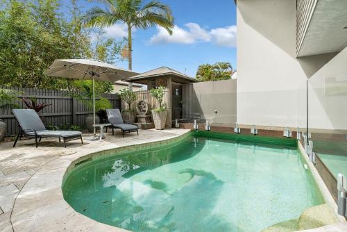 una piscina con dos sillas y una sombrilla en 3 Bora Blue, en Noosaville