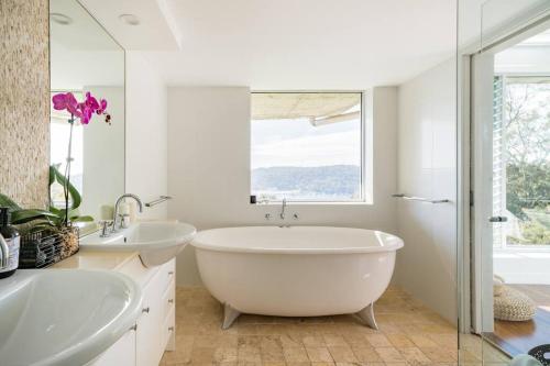 a white bathroom with two sinks and a large window at Sea La Vie at Bayview - 'paradise by the sea' in Bay View