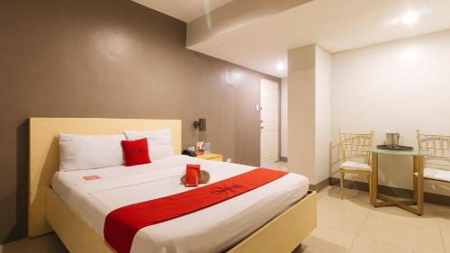 a bedroom with a large bed with a red blanket at RedDoorz at Samat Mandaluyong in Manila