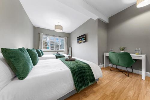 a bedroom with a white bed with green pillows and a desk at London Bridge Apartments in London