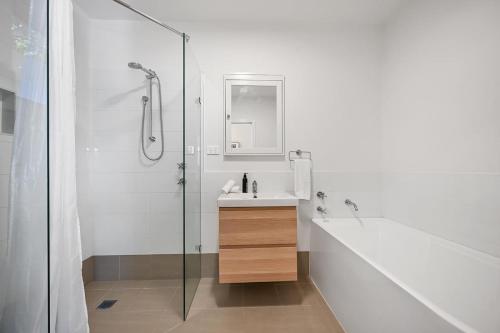Un baño blanco con lavabo y ducha. en Greenwood Cottage - Close to CBD, Leafy Backyard, en Bathurst