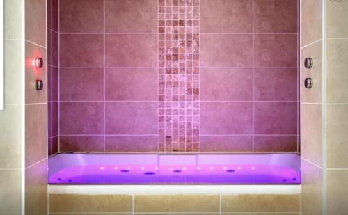 bañera púrpura con iluminación púrpura en el baño en Clamshell Land - Royal Mile en Edimburgo