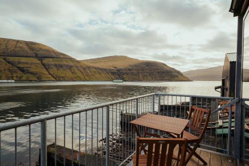 una mesa y sillas en un balcón con vistas a un cuerpo de agua en Charming Boathouse with Panoramic Fjord Views, en Vestmanna