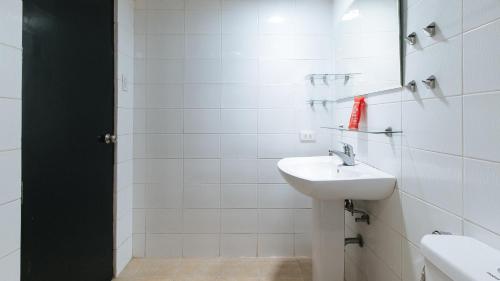 a white bathroom with a sink and a mirror at RedDoorz at Samat Mandaluyong in Manila