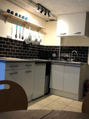 a kitchen with white cabinets and black tiles at B&B Chalet Les Frenes in Chamonix-Mont-Blanc