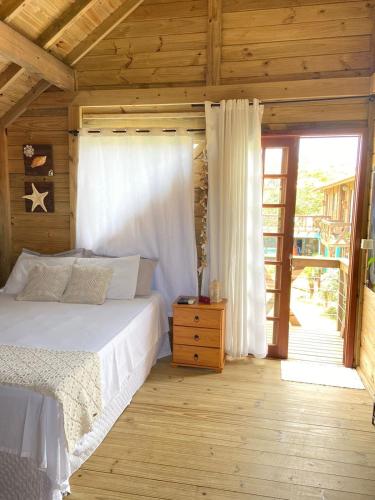 a bedroom with a bed in a wooden cabin at Villa Rosa e Mar - Praia do Rosa in Imbituba