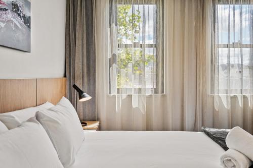 a bedroom with a white bed and a window at Prince of Wales Hotel in Hobart