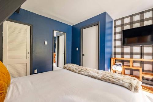 a bedroom with blue walls and a large bed at Camp Smores- Modern A-Frame with Pool in Newfield