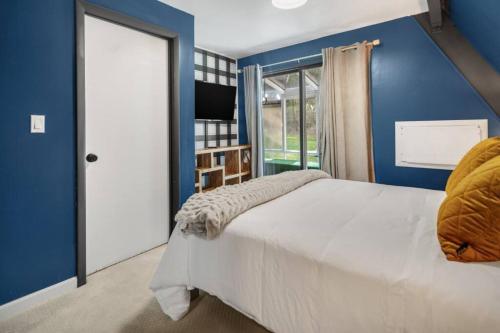 a blue bedroom with a bed and a window at Camp Smores- Modern A-Frame with Pool in Newfield