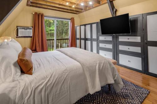 a bedroom with a bed and a flat screen tv at Camp Smores- Modern A-Frame with Pool in Newfield
