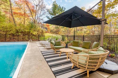 a patio with chairs and an umbrella next to a pool at Camp Smores- Modern A-Frame with Pool in Newfield