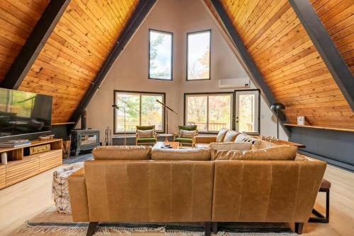 a large living room with a large brown couch at Camp Smores- Modern A-Frame with Pool in Newfield