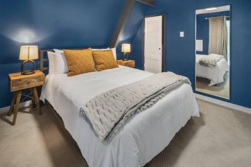 a blue bedroom with a large bed and a mirror at Camp Smores- Modern A-Frame with Pool in Newfield