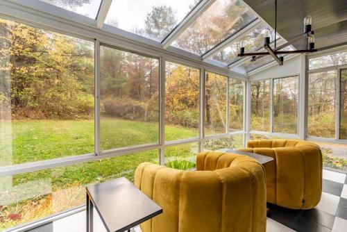 a conservatory with yellow chairs and a table and windows at Camp Smores- Modern A-Frame with Pool in Newfield