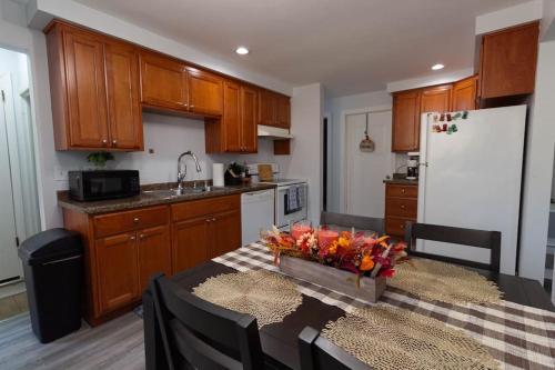a kitchen with wooden cabinets and a table with a vase of flowers at Mi Casa Su Casa, 28 minutes from Lambeau Field! in Appleton