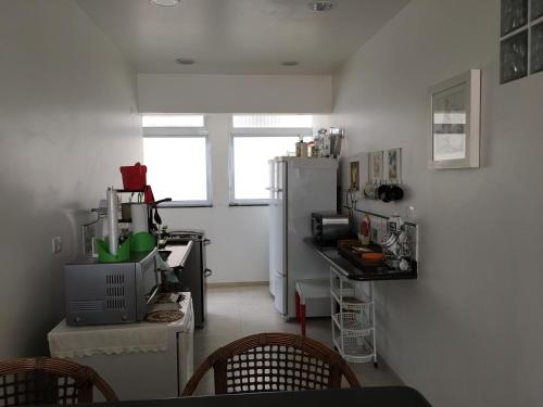 a kitchen with a refrigerator and a table with chairs at Apartamento maravilhoso na Pitangueiras Guarujá in Guarujá