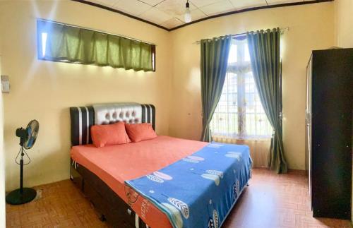 a bedroom with a bed in a room with a window at Malin's Homestay in Bukittinggi