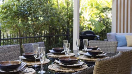 a table with plates and wine glasses on a patio at Azure - Luxe, Pool Beachfront in Kororo Basin