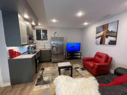 a living room with a red chair and a kitchen at Comfortable and Beautiful Brand-New Suite BSMT-Two Bedroom, Two Washrooms in Calgary
