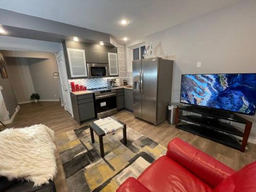 ein Wohnzimmer mit einem roten Sofa und einem großen TV in der Unterkunft Comfortable and Beautiful Brand-New Suite BSMT-Two Bedroom, Two Washrooms in Calgary