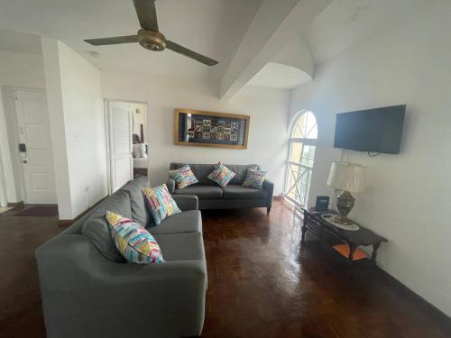 a living room with a couch and a ceiling fan at OceanBreeze Jamaica Penthouse, 7-Minute Walk to Beach in Ocho Rios