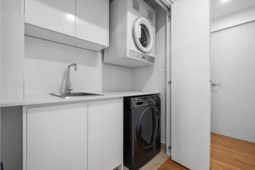 a kitchen with a washing machine and a sink at Centrally Located Pymble Apartment in Pymble